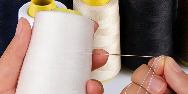 A spool of sewing thread next to a skein of knitting yarn